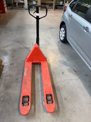 un chariot élévateur dans un garage, avec une voiture en arrière-plan