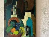un tableau accroché au mur d'une pièce, représentant un vase rempli de fruits et une bouteille
