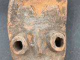 a clay mask with holes in it on a black surface