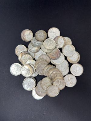 pile of silver coins on a black surface