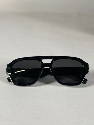 une paire de lunettes de soleil noires posée sur une surface blanche