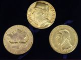 three gold medals are displayed in a display case on a black surface