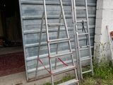 plusieurs échelles appuyées contre un mur devant un garage