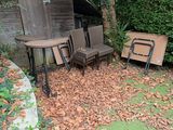 une table et des chaises dans le jardin, avec des feuilles par terre