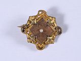 un gros plan d'une broche en or sertie d'une perle