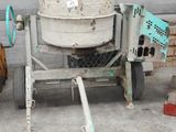 une bétonnière posée sur un chariot devant un immeuble
