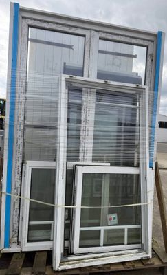 two windows that are sitting on a pallet in the dirt