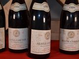 four bottles of wine are lined up on a red table