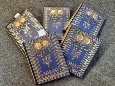 Quatre livres bleus sont posés sur un tapis bordé d'or.