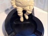 a small statue of a man sitting on top of a ashtray
