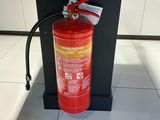 un extincteur posé par terre à côté d'une borne d'incendie