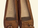 pair of brown shoes with tassels on them on a white surface