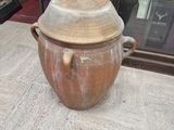 a large brown pot sitting on a table in front of a glass case