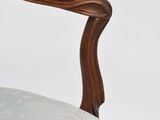 the back of a wooden chair with a blue upholstered seat