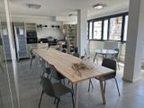 une longue table avec des chaises et un vase posé dessus, au milieu d'une pièce