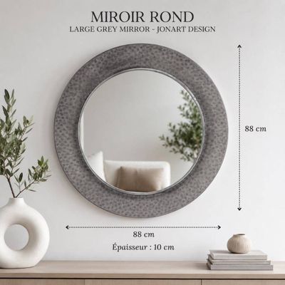 un miroir accroché au mur, à côté d'un vase contenant une plante