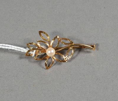 une photo d'une broche en forme de fleur en or ornée d'une perle