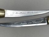 two knives with writing on them sitting next to each other on a table
