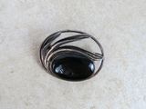 silver and black stone broochle sitting on top of a white surface