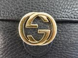 a close up of a black leather bag with a gold gucci logo