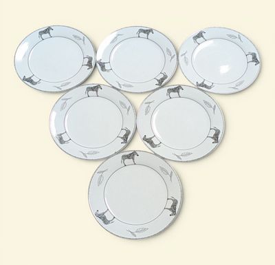 six white plates with horses on them sitting on a table