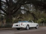a white car driving down the street in front of a tree