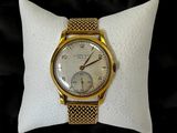 une photo d'une montre-bracelet en or posée sur un oreiller