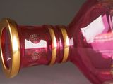 a pink glass vase with gold trimmings on it