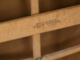 a close up of a wooden chair with a louis vuitton label on it