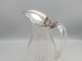 un petit pichet en verre avec une feuille sur l'anse