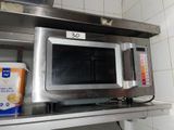 a microwave that is sitting on a shelf in a kitchen