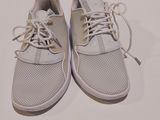 une paire de baskets blanches à lacets posée sur une surface blanche