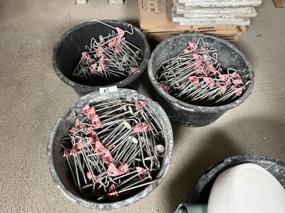 trois seaux remplis d'épingles, posés par terre à côté d'un tas d'autres objets