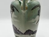 a green vase with a picture of palm trees on it