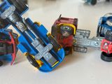 Plusieurs camions miniatures sont alignés sur une surface blanche