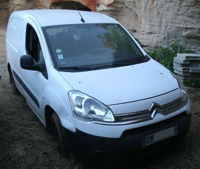 une petite camionnette blanche garée devant un mur de pierre