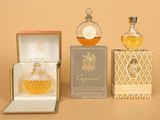 trois flacons de parfum posés sur une table, à côté d'une boîte