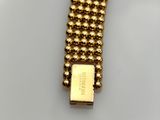 a close up of a gold bracelet on a white surface