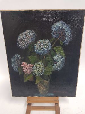 un tableau représentant des fleurs bleues et roses dans un vase posé sur un chevalet