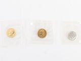three gold and silver coins in plastic bags on a white surface