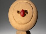 an image of a red stone ring sitting on top of a stand