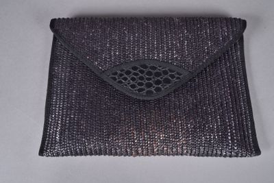 une image représentant un sac à main noir posé sur une surface blanche