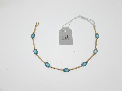 un bracelet en or orné de perles de verre bleues et d'une étiquette de prix
