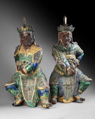two chinese figurines of two men sitting on their knees