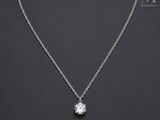 a white diamond pendant on a silver chain on a black background