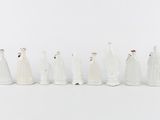 seven figurines of people dressed in white standing in a row