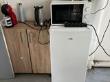 a small white refrigerator and a microwave in a room