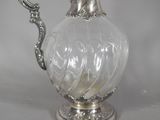 a silver and glass pitcher with a handle on a table