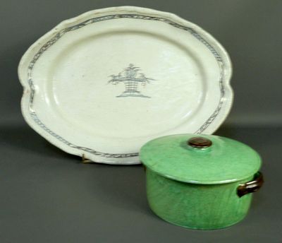 a green pot with a lid next to a plate with a picture of a tree on it