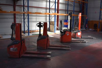 several forklifts are parked in a large warehouse with lots of pallets